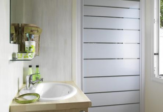 Modernes Badezimmer in einer Glamping-Unterkunft mit Dusche, Waschbecken, Spiegel und Fenster.