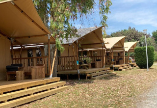 Fila de tiendas safari Wood Lodge con porche en Village Seasonova Bassin d'Arcachon, camping en Francia.
