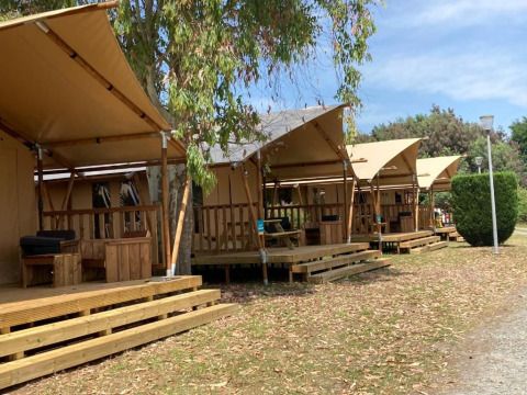 Række af Wood Lodge-safaritelte med veranda på Village Seasonova Bassin d'Arcachon campingplads i Frankrig.