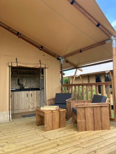 Terraza de madera con asientos frente a una tienda safari Wood Lodge con baño en Village Seasonova Bassin d'Arcachon.