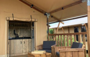 Wooden deck seating area in front of a Wood Lodge safari tent with private bathroom at Village Seasonova Bassin d'Arcachon.