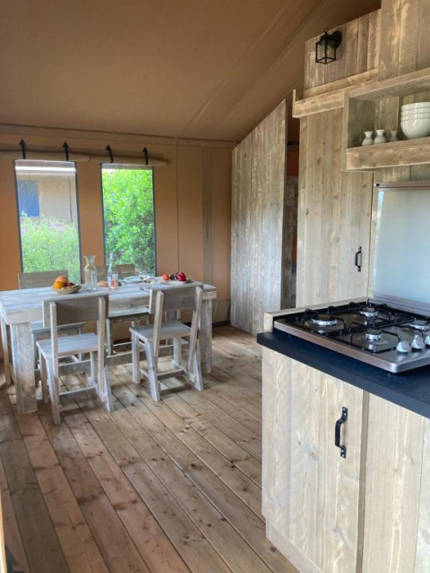 Interior de la tienda safari Wood Lodge con mesa de comedor y cocina en Village Seasonova Bassin d'Arcachon, Francia.