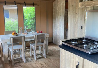 Interior de la tienda safari Wood Lodge con mesa de comedor y cocina en Village Seasonova Bassin d'Arcachon, Francia.