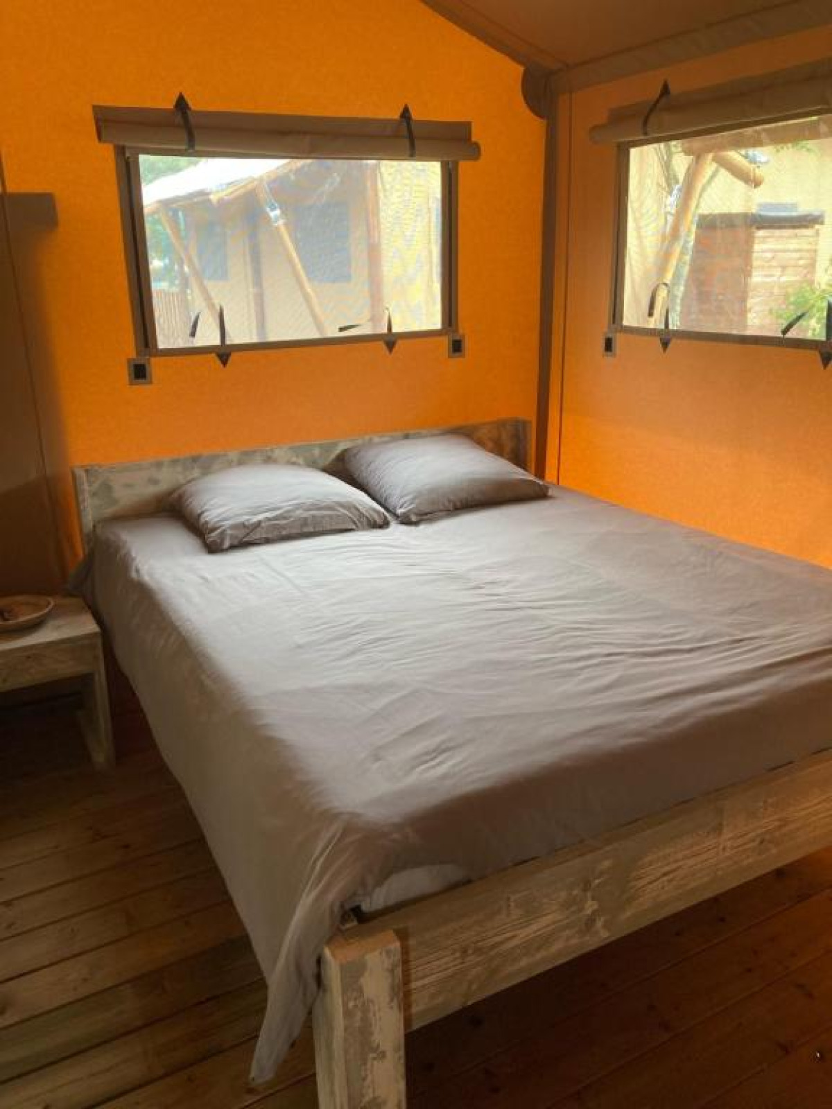 Interieur van safaritent Wood Lodge + met tweepersoonsbed en ramen bij Village Seasonova Bassin d'Arcachon, Frankrijk.