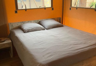 Binnenzicht van een safaritent Wood Lodge + met tweepersoonsbed en ramen aan Village Seasonova Bassin d'Arcachon, Frankrijk.