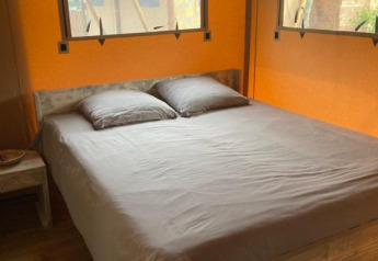 Interior view of a safari tent Wood Lodge + with double bed and windows at Village Seasonova Bassin d'Arcachon, France.