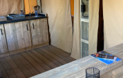 Interiør af en safari telt på Slow Lodge med træmøbler, tekøkken og adskilte sektioner, Village Seasonova Bassin d'Arcachon, Frankrig.