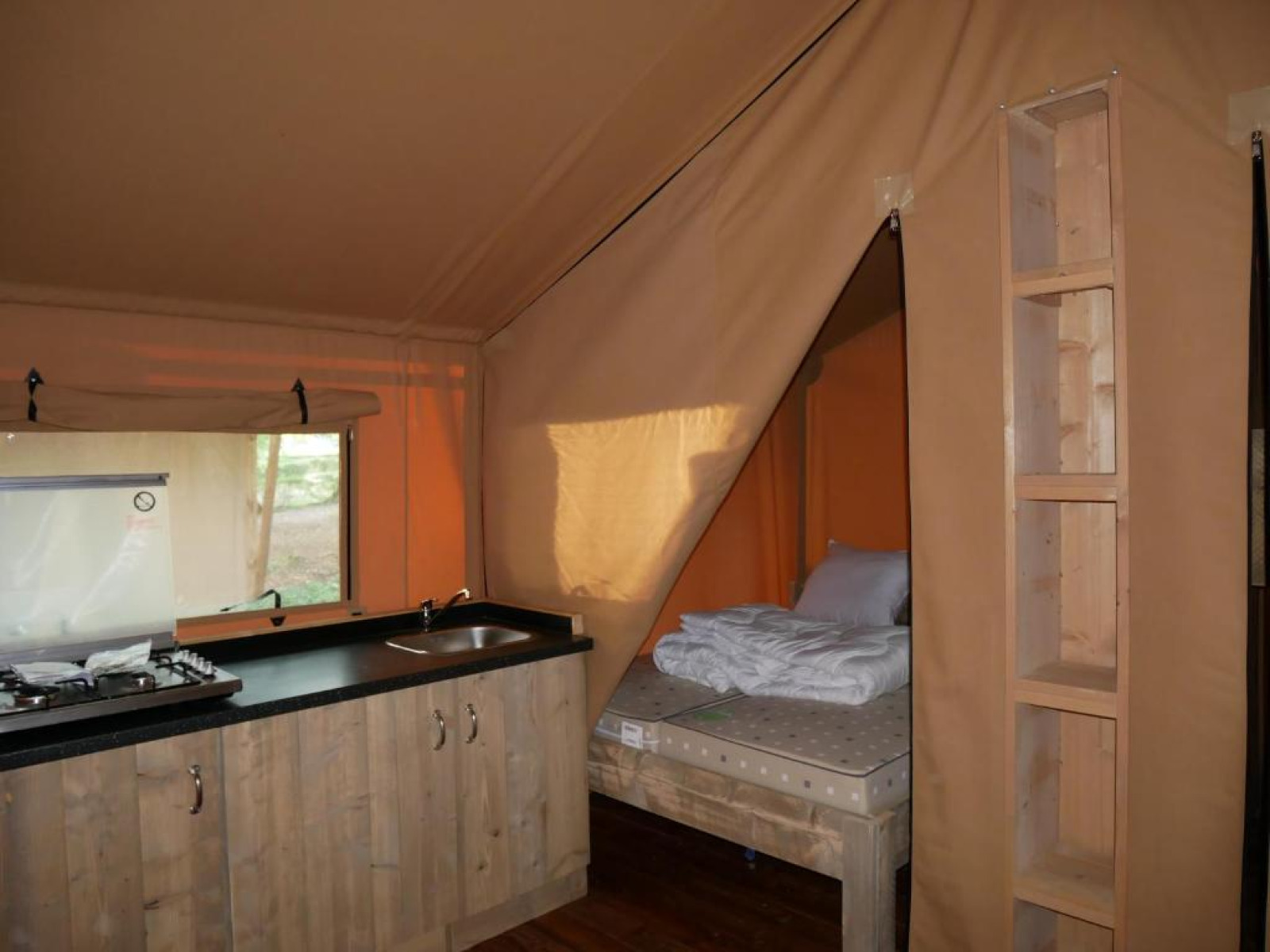 Interieur van een safaritent met keuken en bed bij Slow Lodge op Village Seasonova Bassin d'Arcachon, Frankrijk.