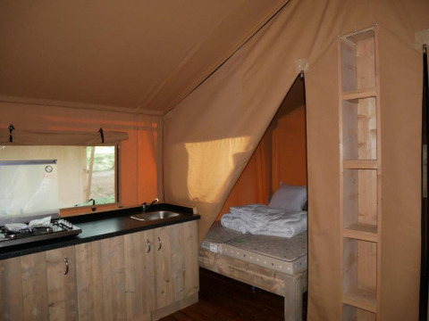 Vista interior de una tienda safari con cocina y cama en Slow Lodge, Village Seasonova Bassin d'Arcachon, Francia.