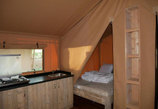 Vista interior de una tienda safari con cocina y cama en Slow Lodge, Village Seasonova Bassin d'Arcachon, Francia.