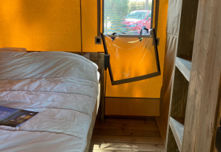 Indvendigt billede af et safari telt på Slow Lodge med trægulv, seng og åbent vindue, Village Seasonova Bassin d'Arcachon.