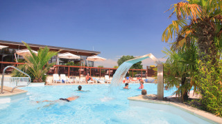Camping Seasonova Haliotis in Normandië, Frankrijk, met zwembad, palmbomen en ligstoelen onder de zon.