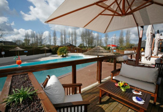 Espace détente extérieur avec meubles en bois et vue sur piscine au Camping Seasonova Haliotis en Normandie.