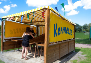 Twee mensen doen mee aan een kermisspel onder geel zeil op Camping Seasonova Haliotis in Normandië, Frankrijk.