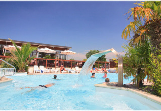 Gäste entspannen im Pool mit Palmen und Wasserfall im Camping Seasonova Haliotis in der Normandie, Frankreich.