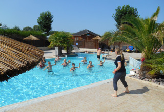 Urlauber entspannen im Pool, während eine Trainerin am Rand steht, im Camping Seasonova Haliotis, Normandie, Frankreich.