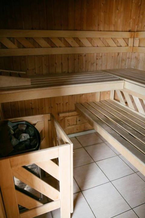 Sauna revestida de madera con bancos y calentador de piedras en Camping Seasonova Haliotis en Normandía, Francia.