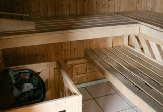Saunaraum mit Holzbänken und Heizer im Camping Seasonova Haliotis, einem Ferienpark in der Normandie, Frankreich.