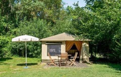 Tienda de campaña con mesa y sillas de madera al aire libre, rodeada de vegetación en Pays de la Loire, Francia.
