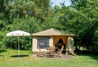 A cozy canvas tent with outdoor table and chairs, surrounded by greenery at Pays de la Loire, France campsite.