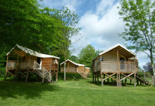 Drie verhoogde houten chalets bij Camping Seasonova Les Plages de Loire, omringd door natuur in Frankrijk.