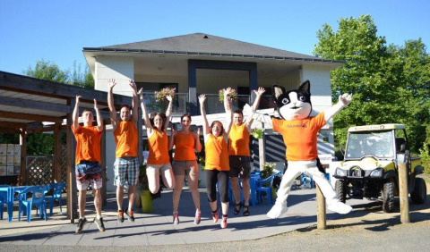 Staff con magliette arancioni e mascotte di gatto saltano davanti a Camping Seasonova Les Plages de Loire in Francia.
