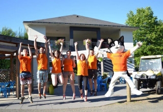 Staff in orange shirts and a cat mascot jump in front of Camping Seasonova Les Plages de Loire, Pays de la Loire, France.