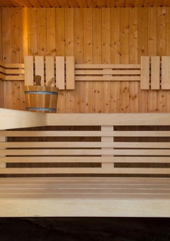 Interior view of a modern wooden sauna with benches and a bucket at Camping Seasonova Les Plages de Loire.