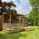 Udendørs billede af Premium Cottage lodge med træterrasse og grønne omgivelser under en skyet himmel.