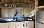 Keukenhoek in safari tent Wood Lodge bij Camping Seasonova Haliotis, Frankrijk, met houten kastjes en koelkast.