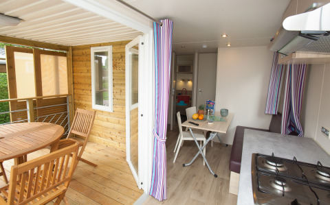 Binnen- en buitenzicht van Cottage Soleo-lodge bij Camping Seasonova Haliotis, Frankrijk, met eettafels.