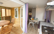 Indoor and outdoor view from Cottage Soleo lodge at Camping Seasonova Haliotis, France, showing dining areas.