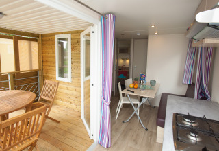 Binnen- en buitenzicht van Cottage Soleo-lodge bij Camping Seasonova Haliotis, Frankrijk, met eettafels.
