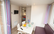 Innenansicht der Lodge Cottage Soleo im Camping Seasonova Haliotis in Frankreich mit Tisch und Sofa.