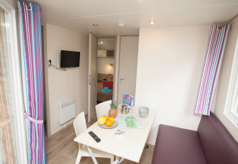 Indvendigt billede af Cottage Soleo-lodgen på Camping Seasonova Haliotis i Frankrig, med spisebord.