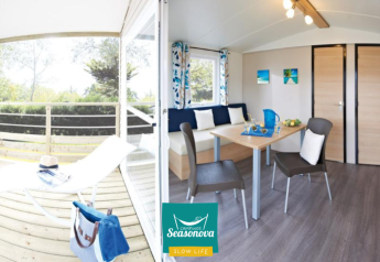 Licht, modern interieur van Cottage Zen lodge met terras, eettafel en zithoek op een zomerse dag.
