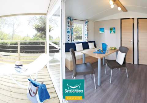 Interior luminoso y moderno de la cabaña Cottage Zen con terraza, mesa de comedor y zona lounge en verano.