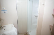 Small bathroom with shower and sink at Cottage Zen in Camping Seasonova Haliotis, France, white walls.