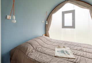 Dormitorio en una tienda safari Coco Sweet en Camping Seasonova Haliotis en Francia, con cama doble y ventana.