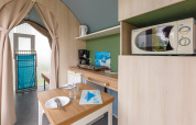 Vista interior de una tienda safari Coco Sweet con cocina y comedor en Camping Seasonova Haliotis, Francia.