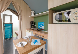 Vista interior de una tienda safari Coco Sweet con cocina y comedor en Camping Seasonova Haliotis, Francia.