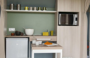 Pequeña cocina en una tienda safari en Camping Seasonova Haliotis, Francia, con microondas y mesa.