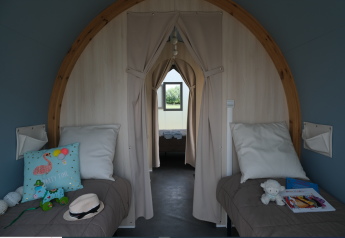 Indvendigt billede af et safari-telt med to enkeltsenge, puder og børnelegetøj på Camping Seasonova Haliotis, Frankrig.