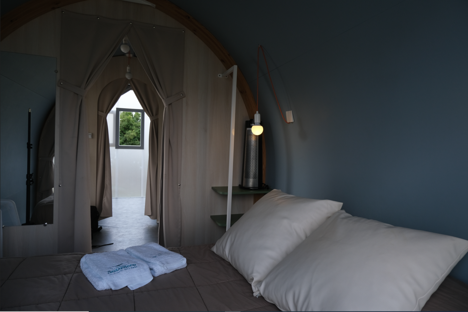 Interieur van een safaritent bij Slow Life Stay op Camping Seasonova Haliotis in Frankrijk, met bed en gordijnen.