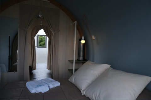Interior de tienda safari en Slow Life Stay, Camping Seasonova Haliotis, Francia, con cama y cortinas visibles.