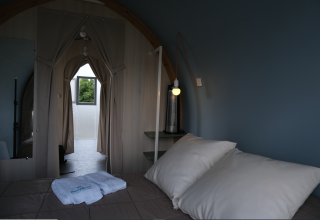 Interior de tienda safari en Slow Life Stay, Camping Seasonova Haliotis, Francia, con cama y cortinas visibles.