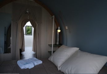 Interieur van een safaritent bij Slow Life Stay op Camping Seasonova Haliotis in Frankrijk met bed en gordijnen.