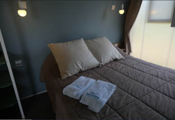 Bedroom inside a Slow Life Stay safari tent at Camping Seasonova Haliotis in France with a made double bed.