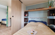 Dormitorio en la cabaña Corfou en Camping Seasonova Les Plages de Loire, con cama king size y estanterías.