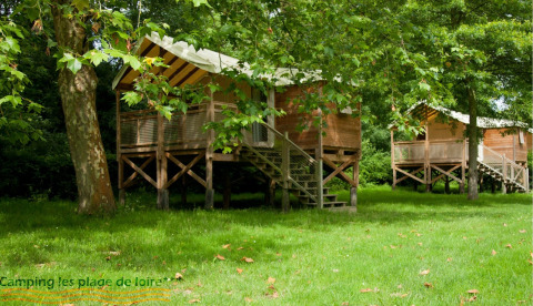 Eco lodge cabins among trees at Camping Seasonova Les Plages de Loire in France, lush green summer scene.